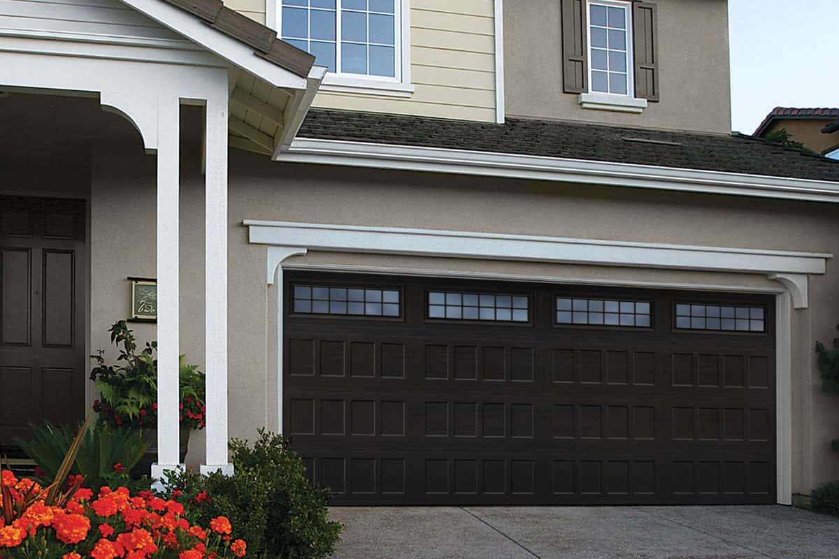 Tan house with a brown garage door that has recessed panels